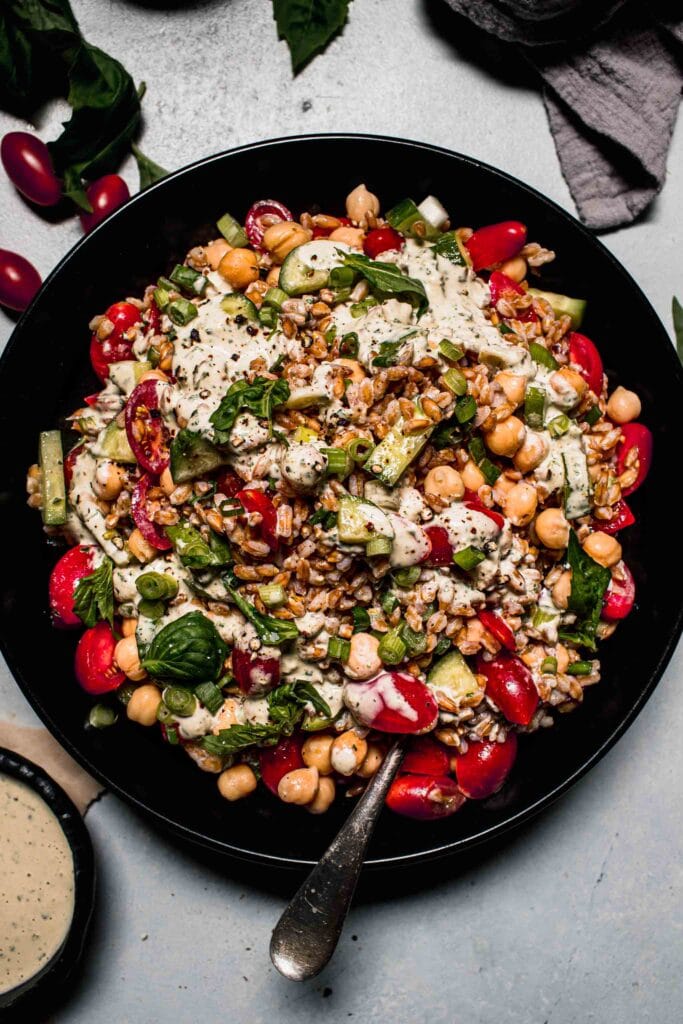 Overhead shot of farro salad in large black bowl with spoon.