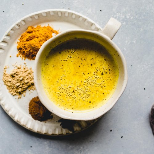 Golden milk latte in mug next to spices.