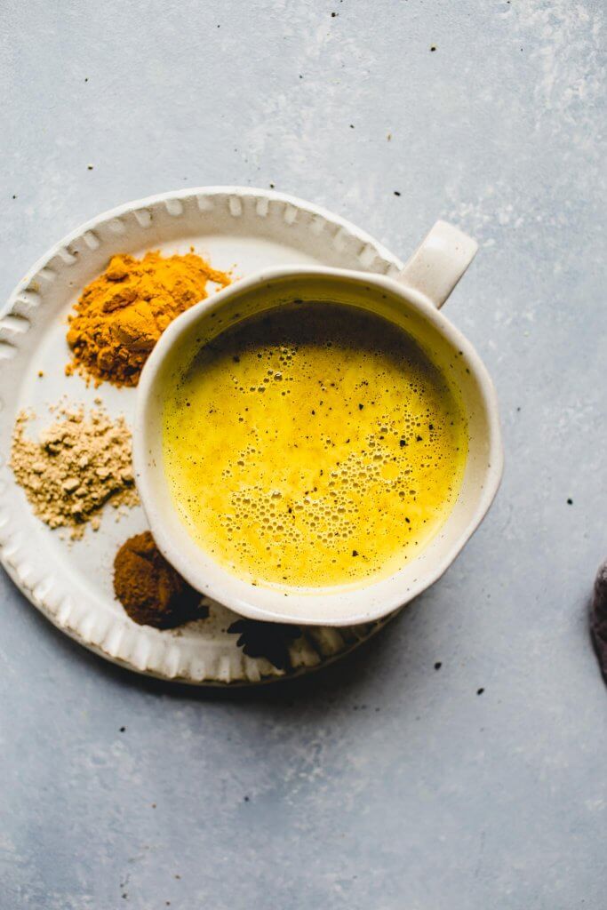 Golden milk latte in mug next to spices.