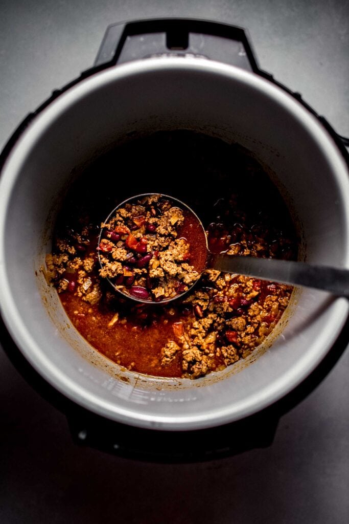 Chili in instant pot with ladle. 