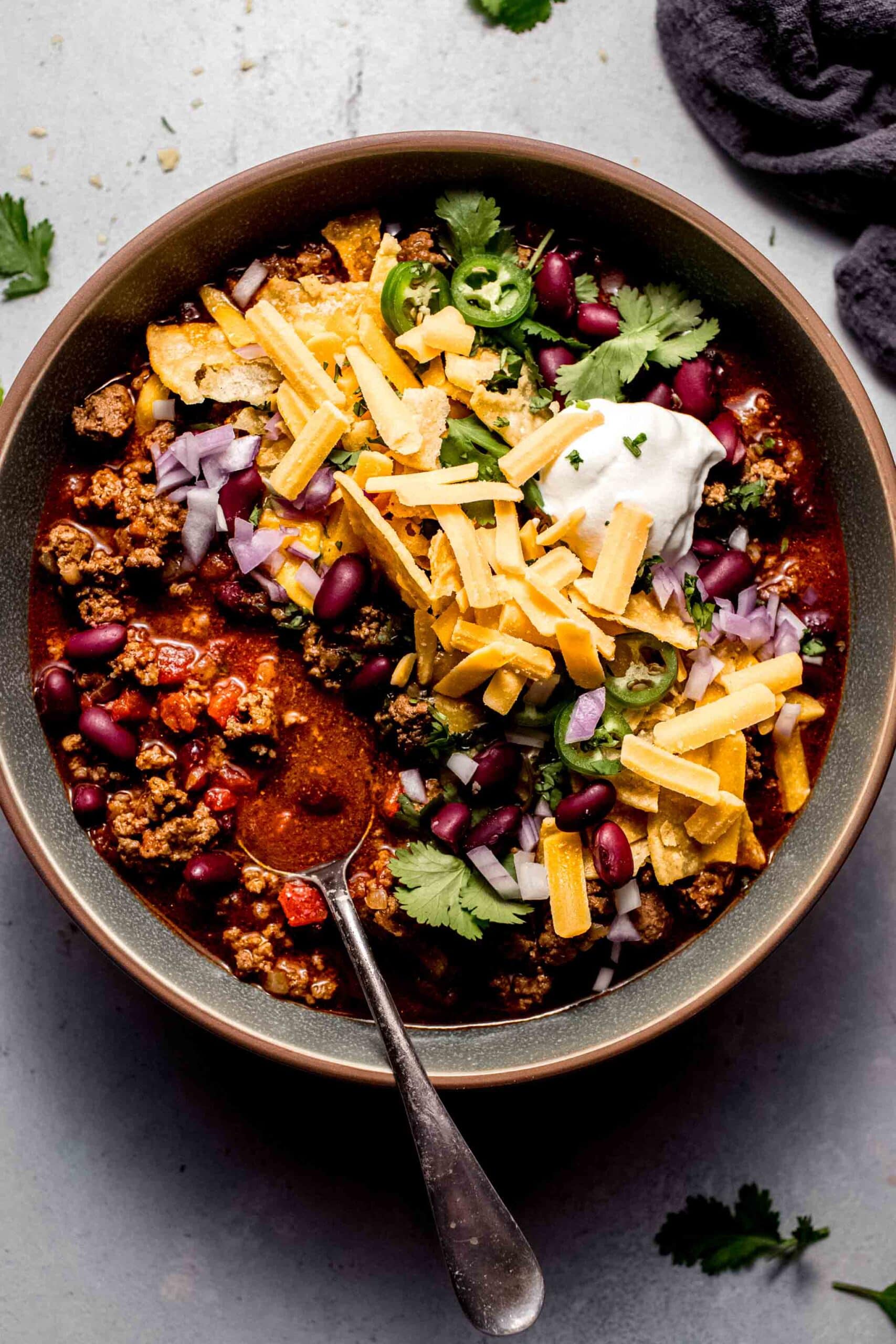Instant pot chili in bowl with sour cream, cheese and onions.