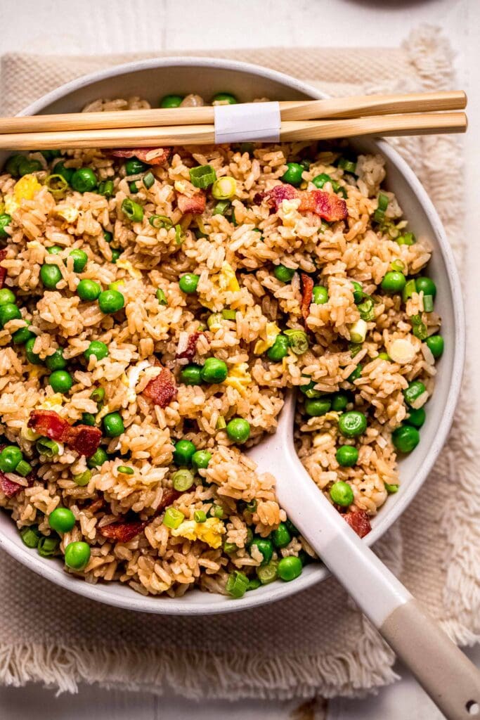 Instant pot fried rice in serving bowl with spoon next to chopsticks.