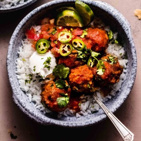 Albondigas in blue bowl topped with sour cream and jalapenos.