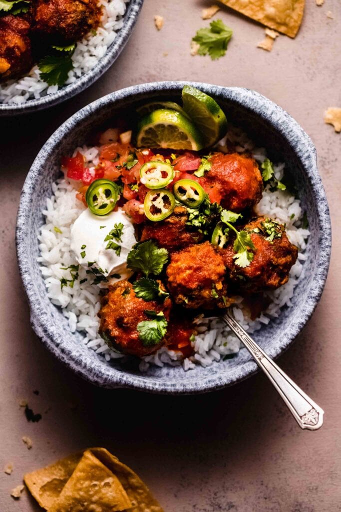 Albondigas in blue bowl topped with sour cream and jalapenos.