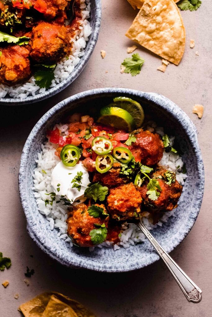 Two bowls with rice topped with spanish meatballs. 