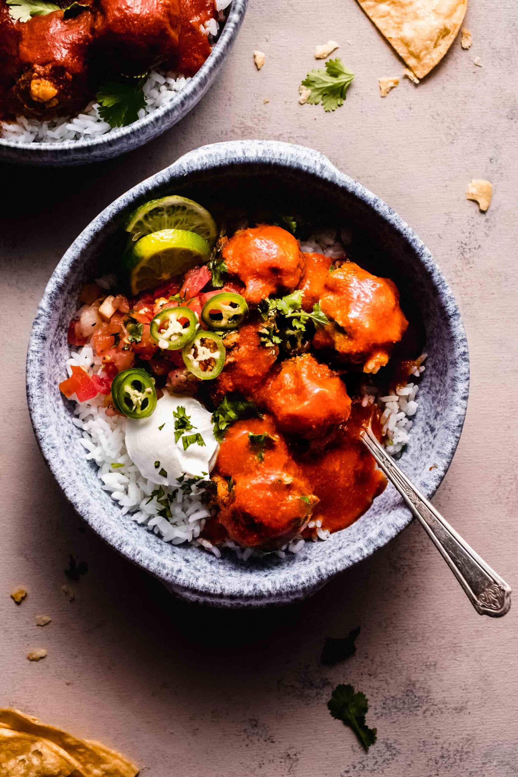 Spanish meatballs served in bowl with rice and a dollop of sour cream.