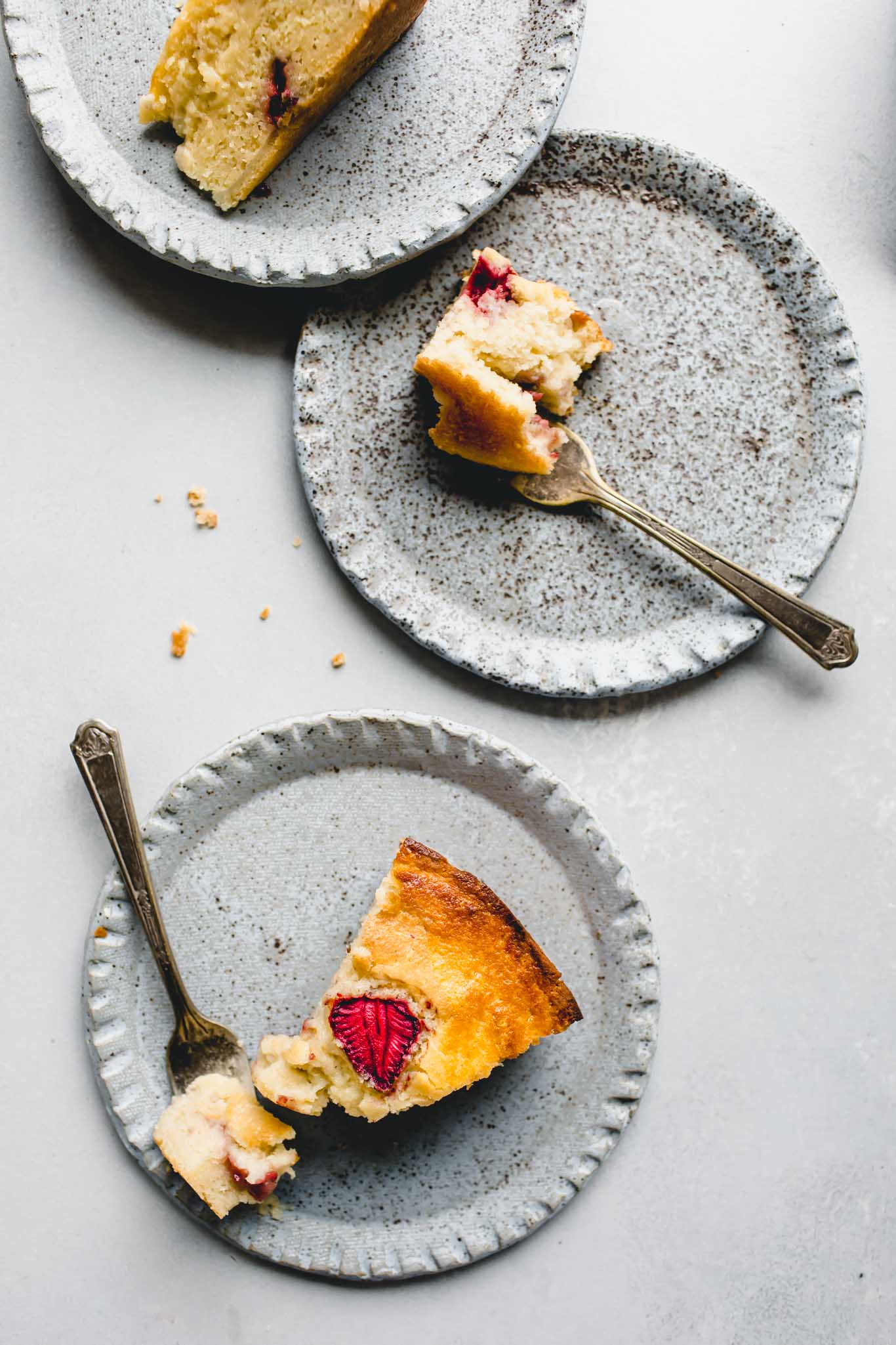 Three pieces of strawberry ricotta cake on blue plates.