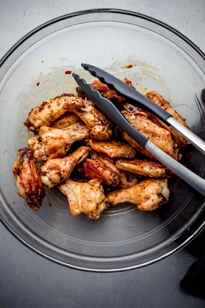 Wings in bowl tossed with sauce. 