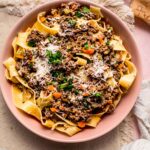 Bowl of pasta topped with white bolognese sauce and parmesan cheese.