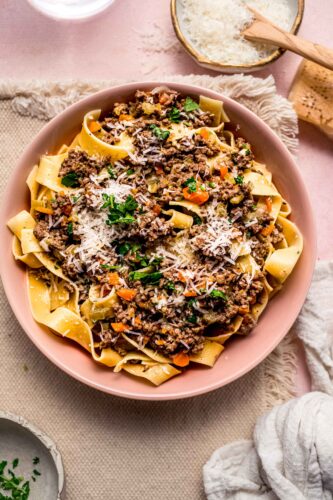 Bowl of pasta topped with white bolognese sauce and parmesan cheese.