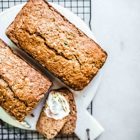 Two loaves of zucchini bread spread with butter.