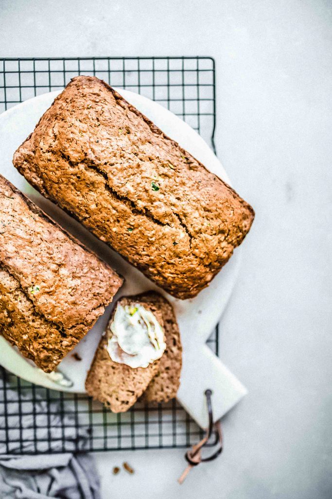 Two loaves of zucchini bread spread with butter.