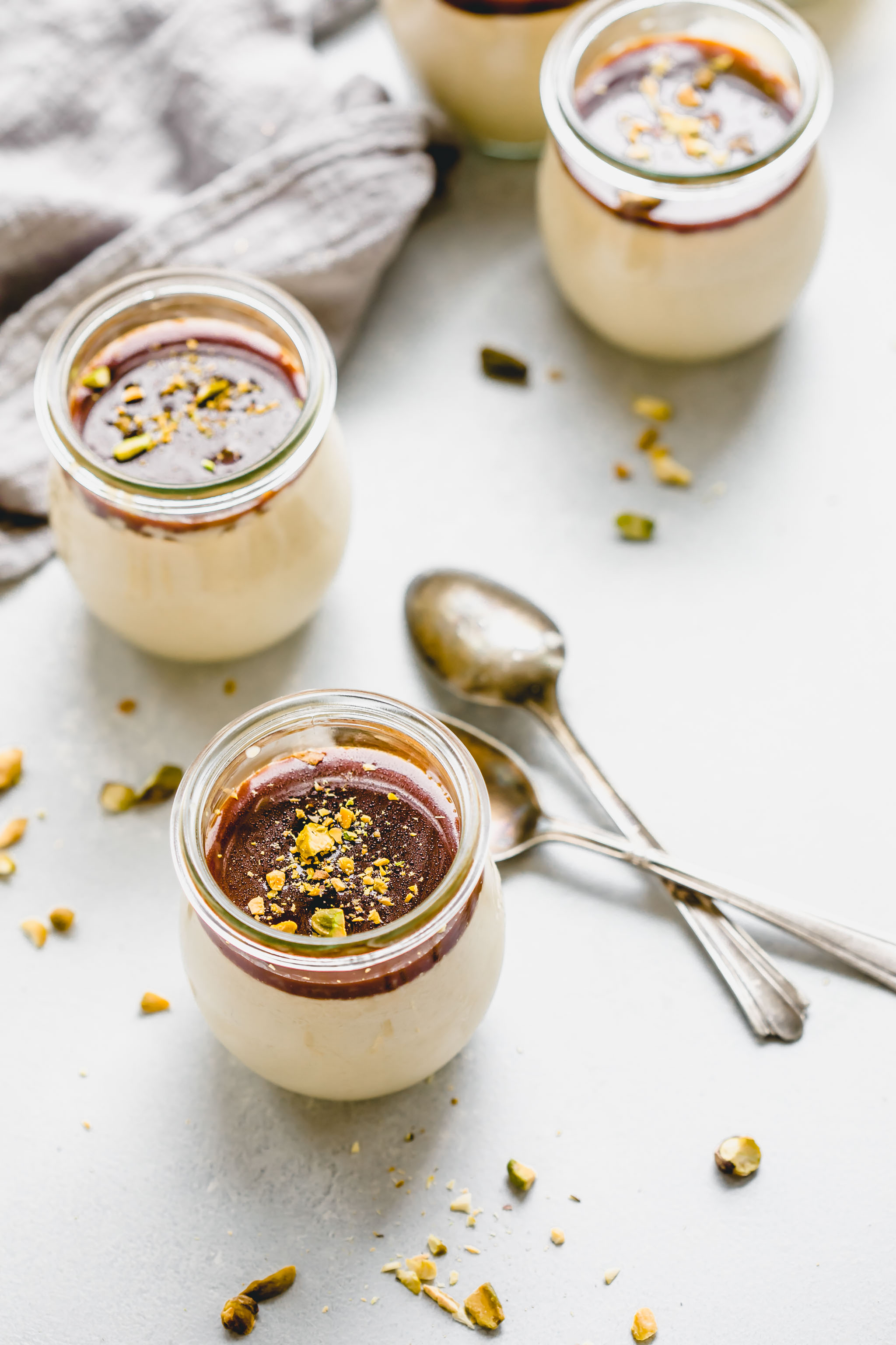 Side view of three jars of butterscotch budino topped with pistachios and salted caramel. 