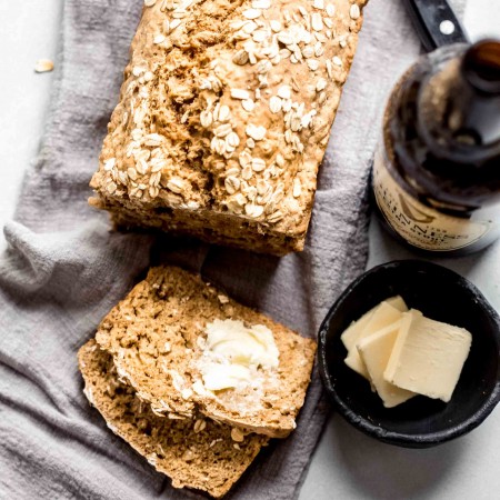 Overhead shot of guinness bread next to bottle of beer and pats of butter.