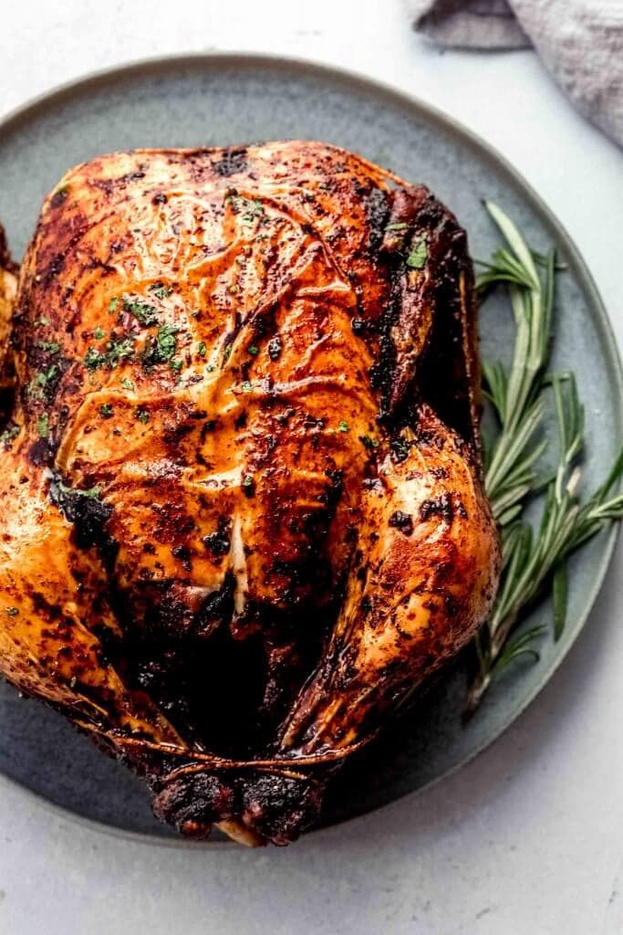 Roasted chicken on grey serving plate with sprig of rosemary.