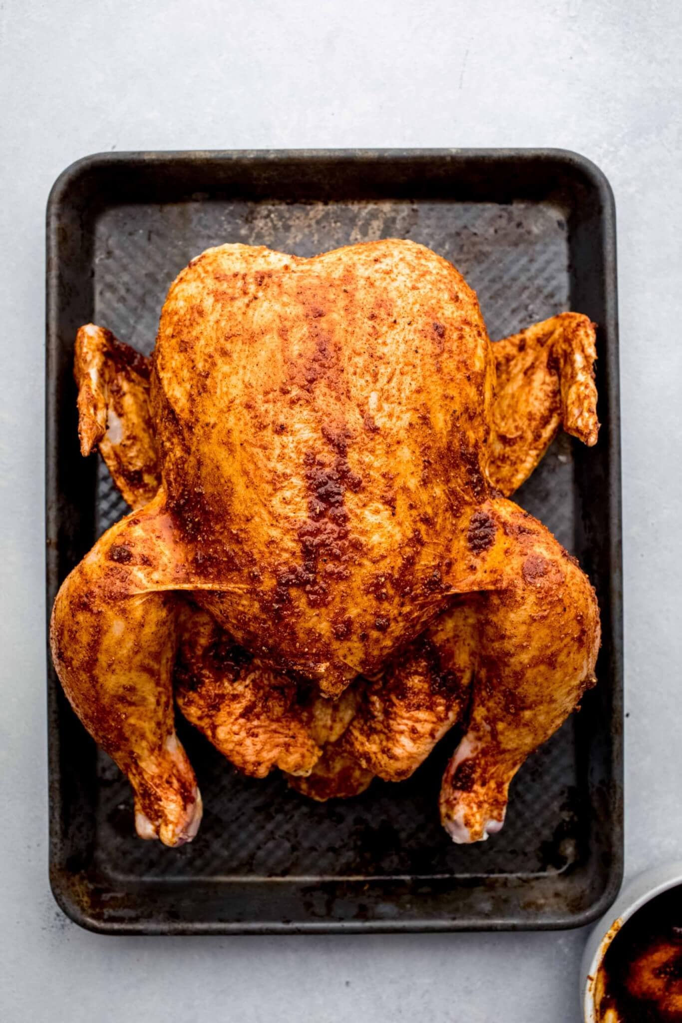 Chicken on baking tray rubbed with spices.