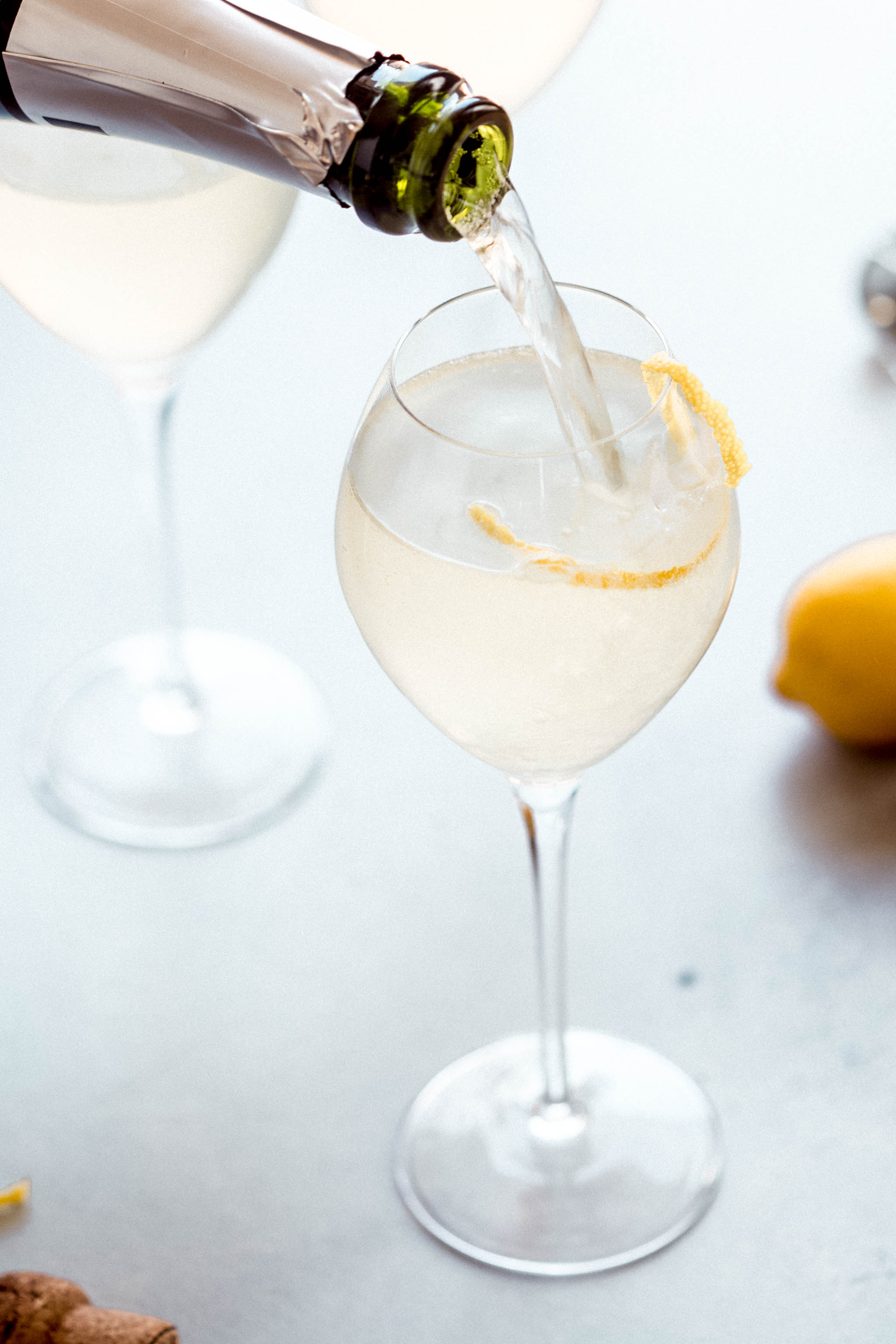 Bottle of sparkling wine pouring into cocktail glass.