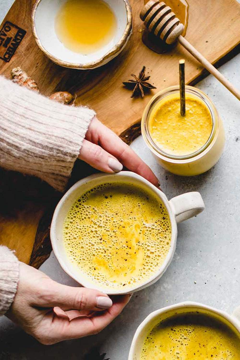 HANDS HOLDING MUG OF GOLDEN MILK