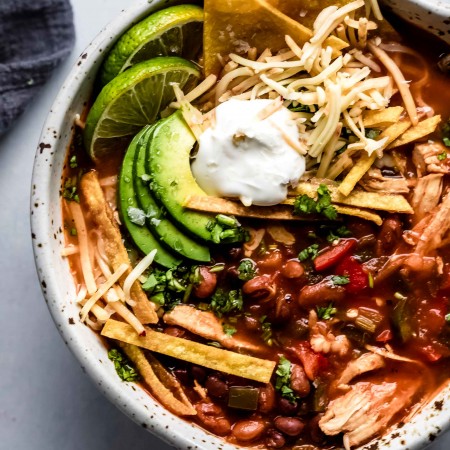 Overhead close up of bowl of Instant Pot Chicken Tortilla Soup topped with avocado, tortilla chips and sour cream.