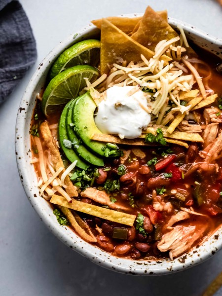 Overhead close up of bowl of Instant Pot Chicken Tortilla Soup topped with avocado, tortilla chips and sour cream.