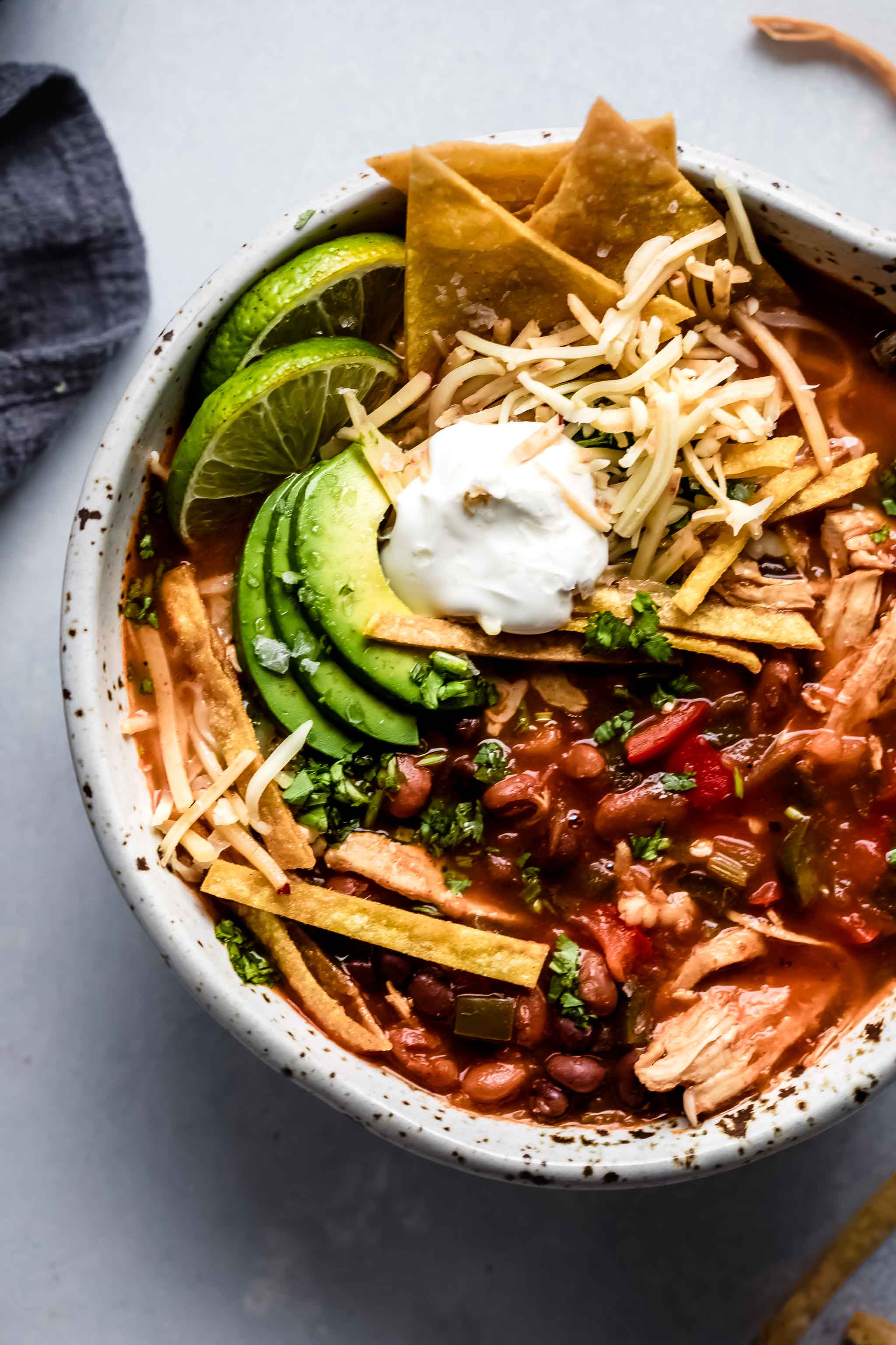 Overhead close up of bowl of Instant Pot Chicken Tortilla Soup topped with avocado, tortilla chips and sour cream.