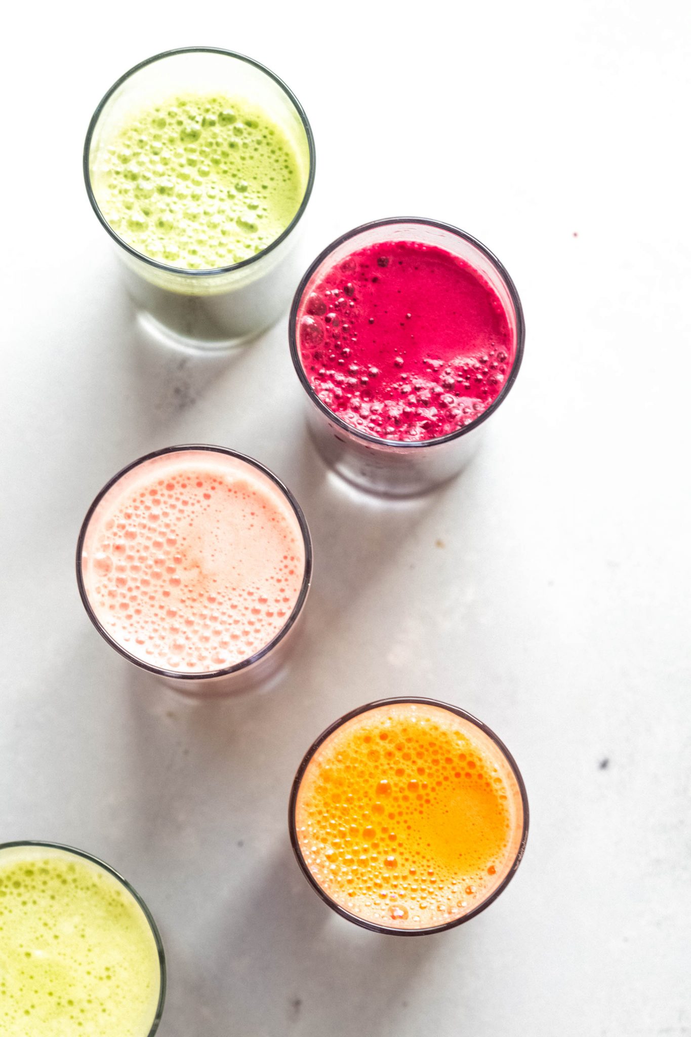 Five different colorful juices in a row shot from overhead.