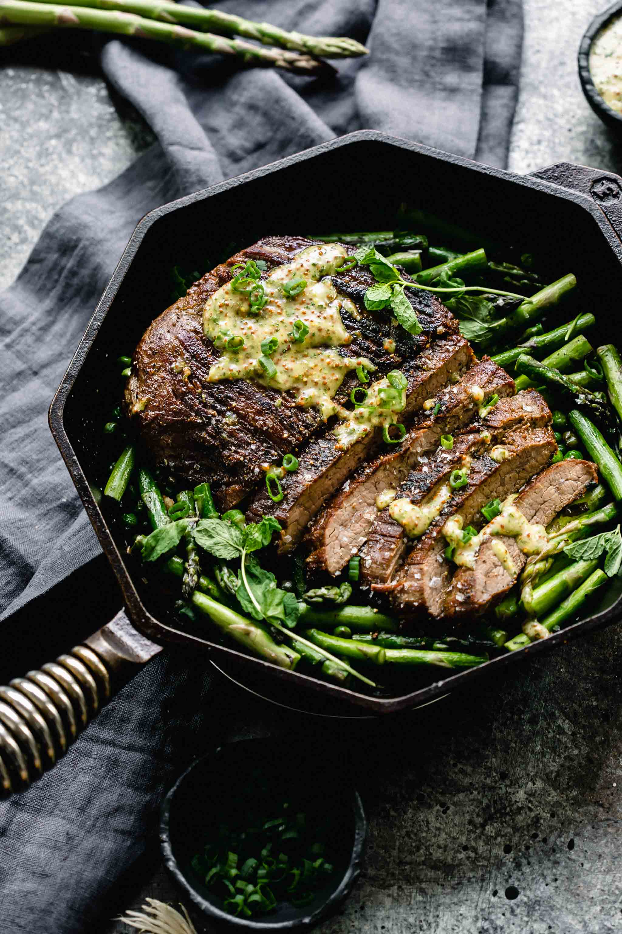 Skillet steak with mint mustard sauce drizzled on it.