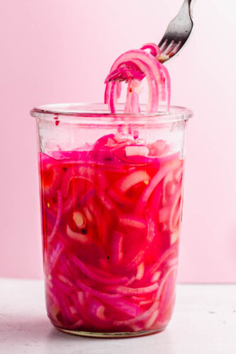 Fork taking pickled onions out of jar.