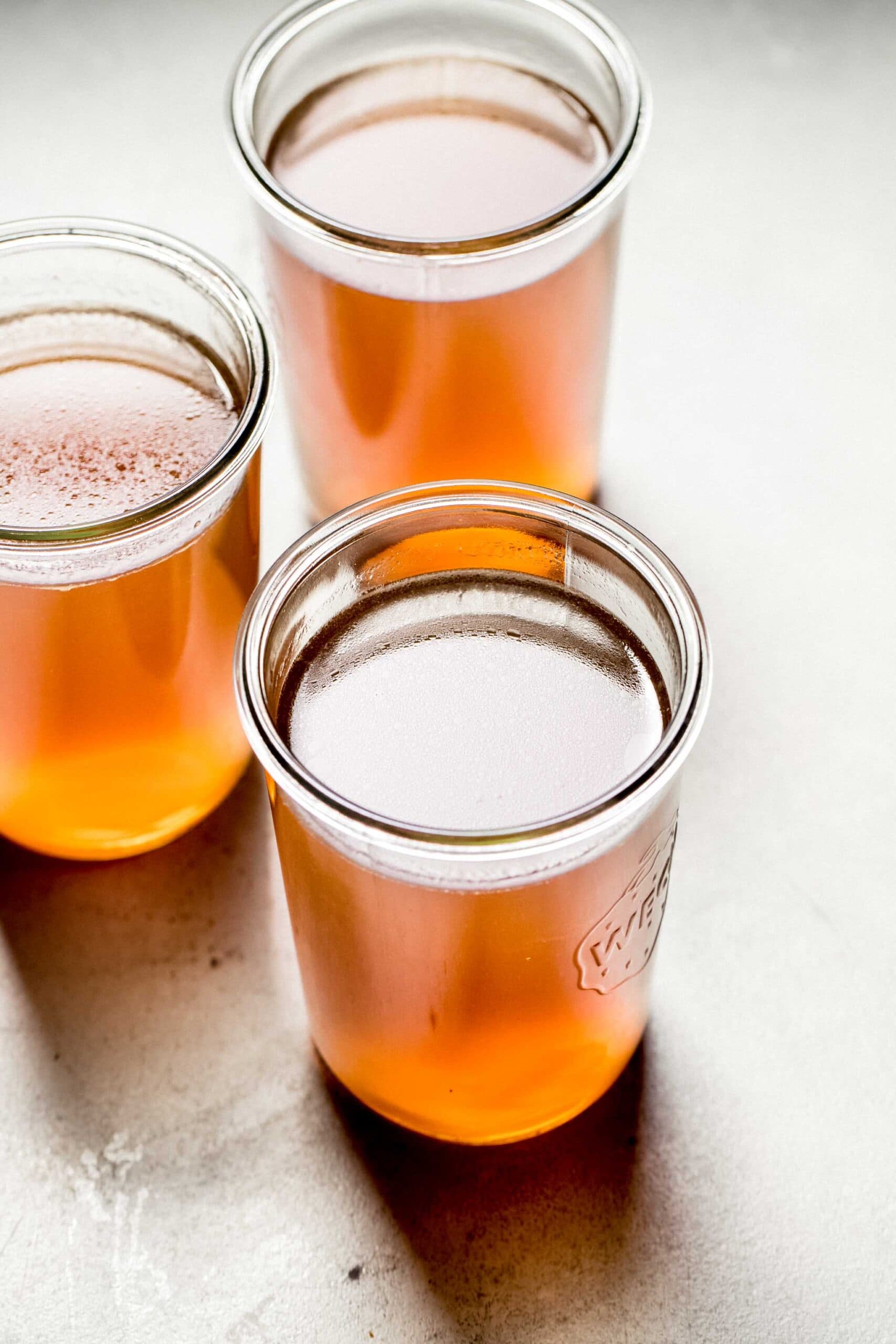 Three jars of slow cooker bone broth on counter.