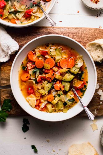 Overhead shot of 2 bowls of weight loss soup on counter next to bowl of pepper flakes.