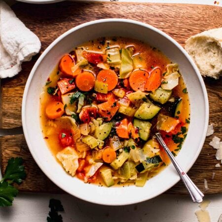 Overhead shot of 2 bowls of weight loss soup on counter next to bowl of pepper flakes.