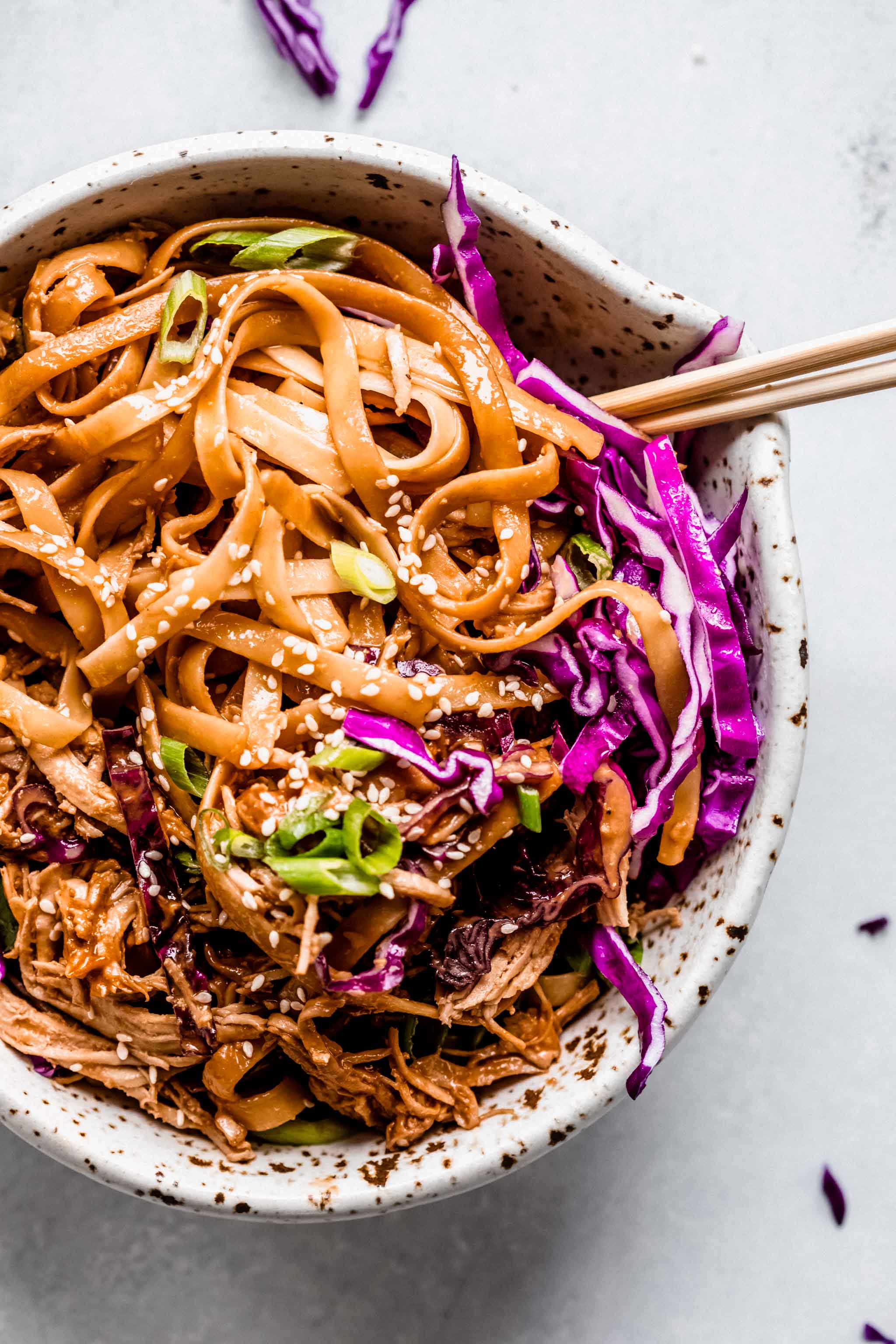 Overhead close up of bowl of sesame noodles with chopsticks.