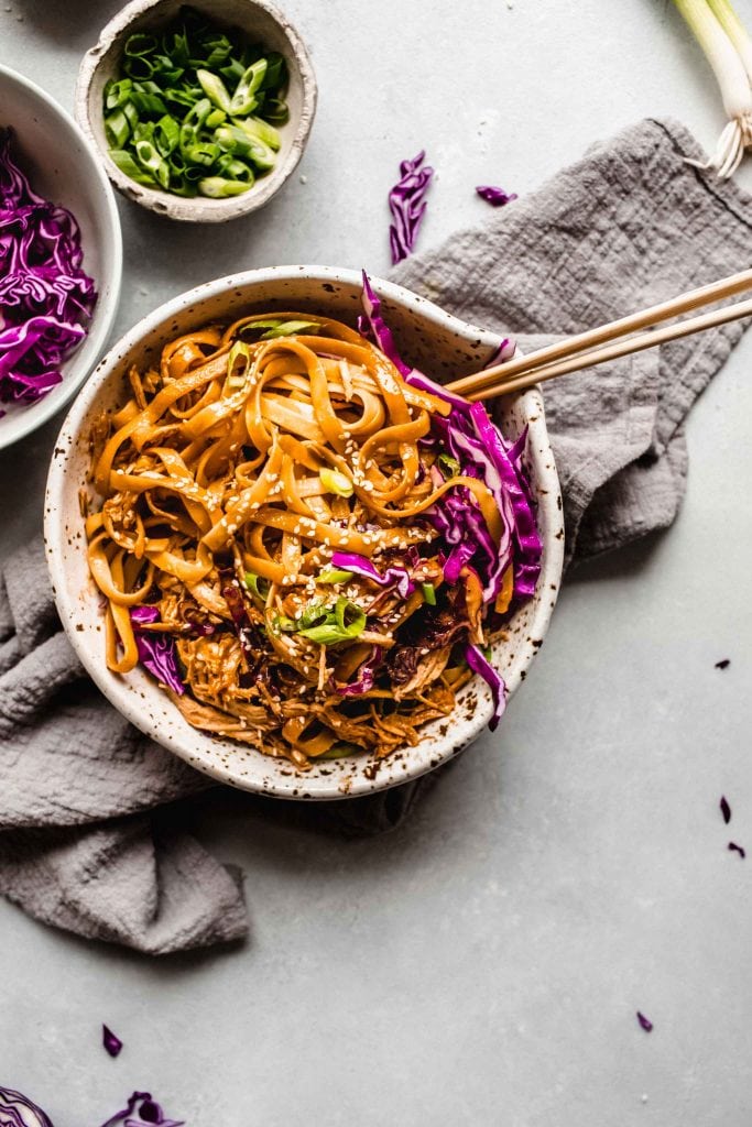 Overhead close up of bowl of sesame noodles with chopsticks.