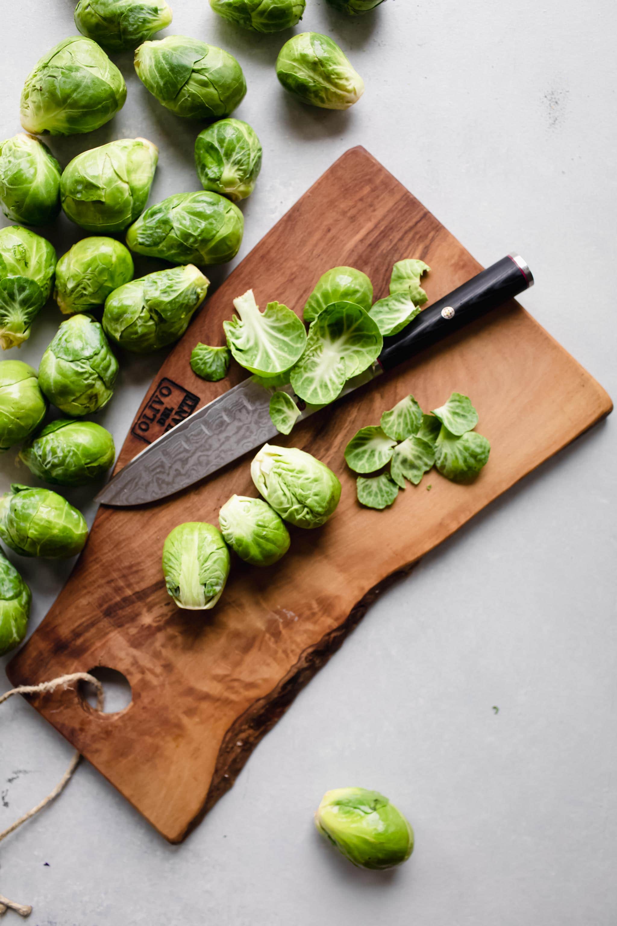 Brussel sprouts being trimmed on cutting board. 