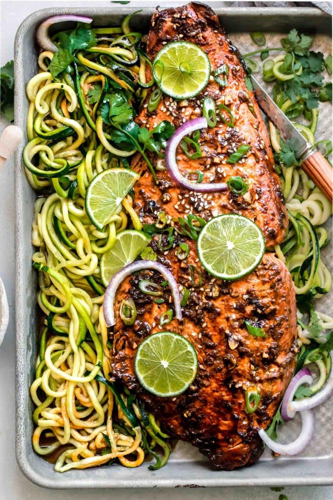 Overhead close up of salmon with glaze and sesame seeds topped with limes.