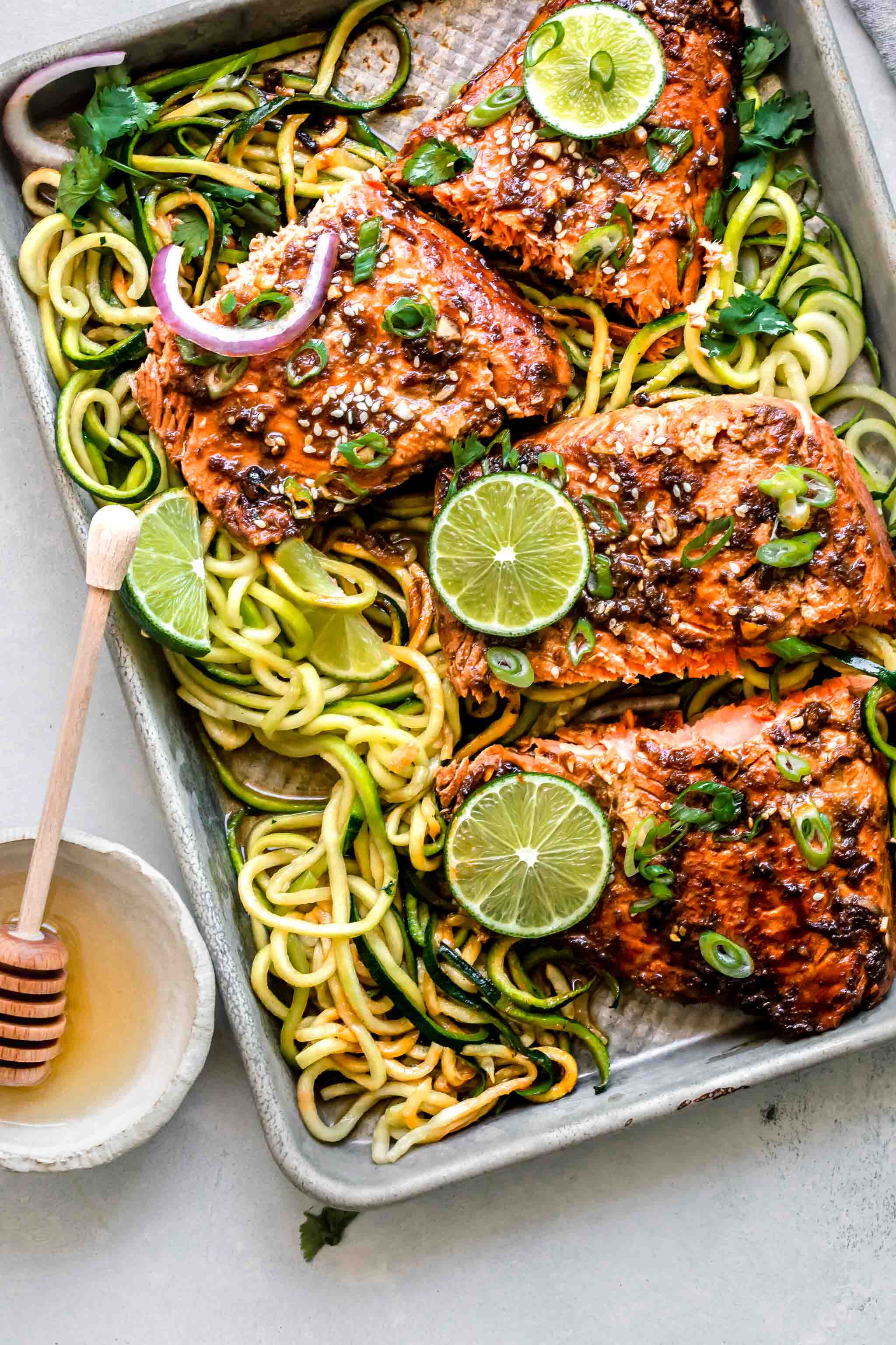 Overhead shot of salmon sliced on baking sheet with zucchini noodles.