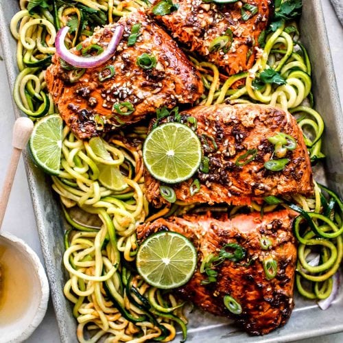Overhead shot of salmon sliced on baking sheet with zucchini noodles.