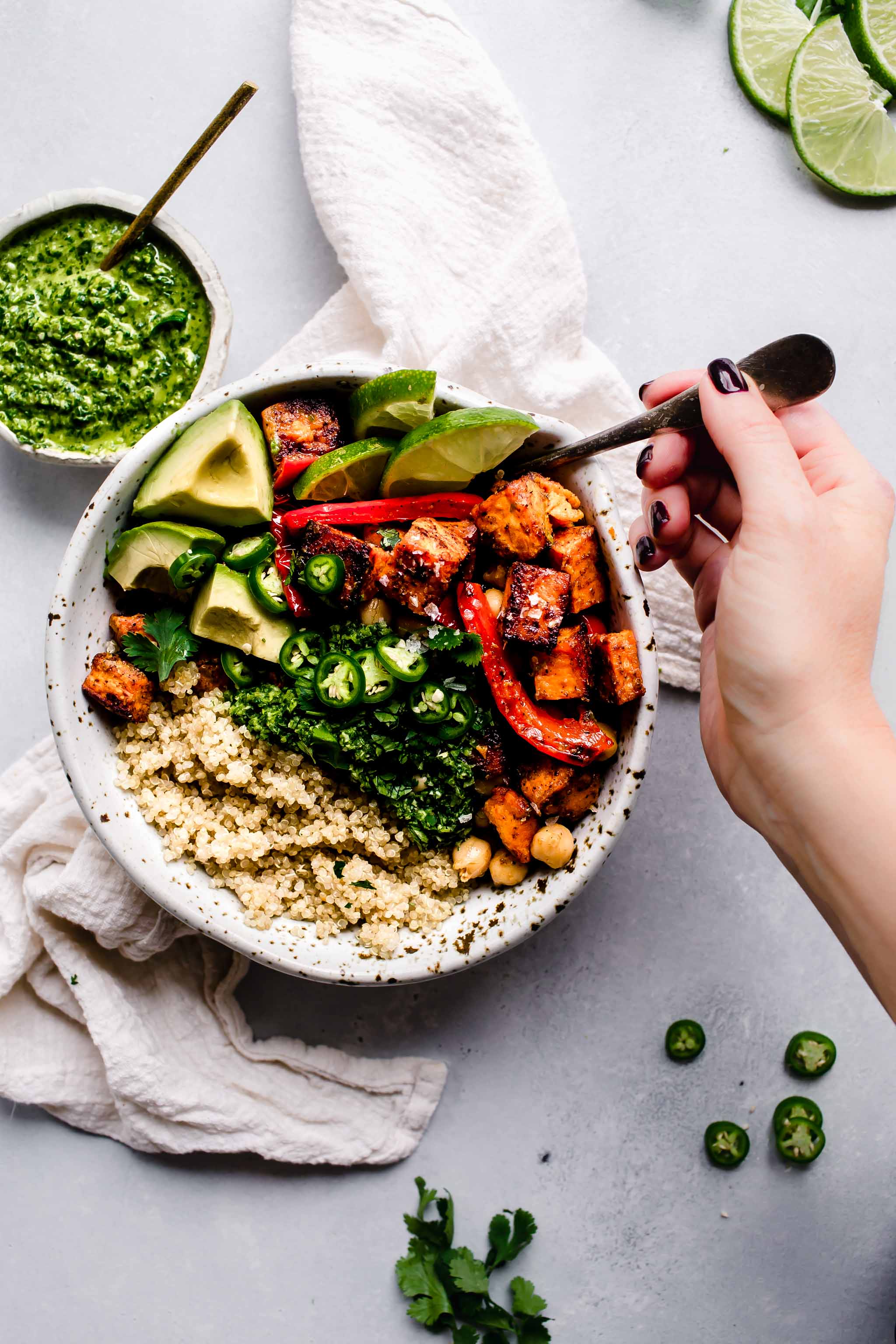 Hand holding fork digging into buddha bowl.