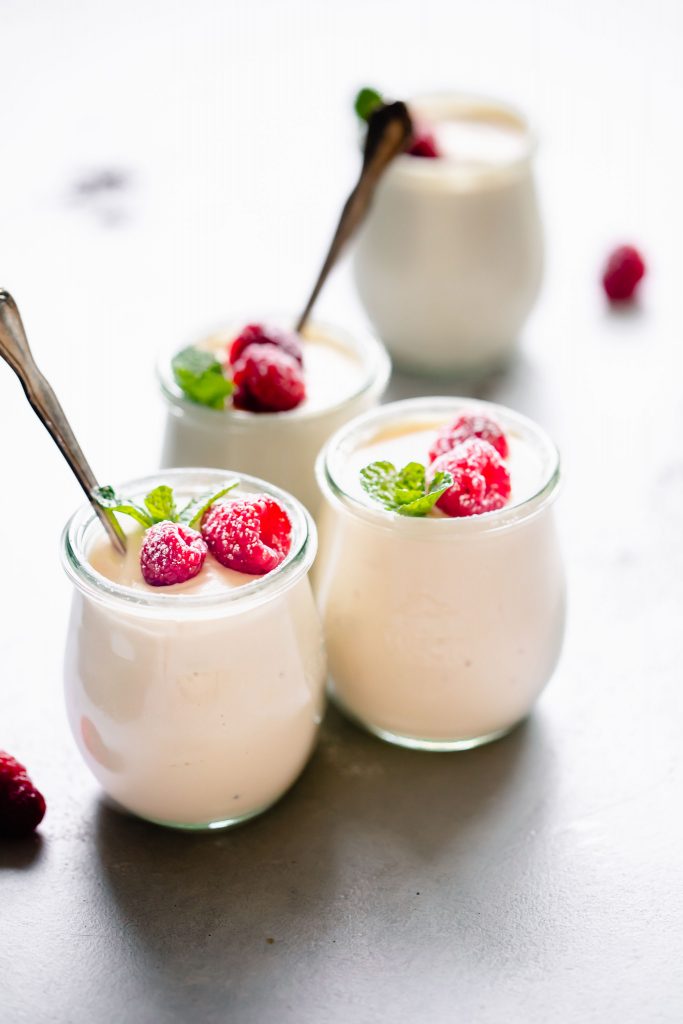 Four jars of ricotta mousse topped with raspberries.