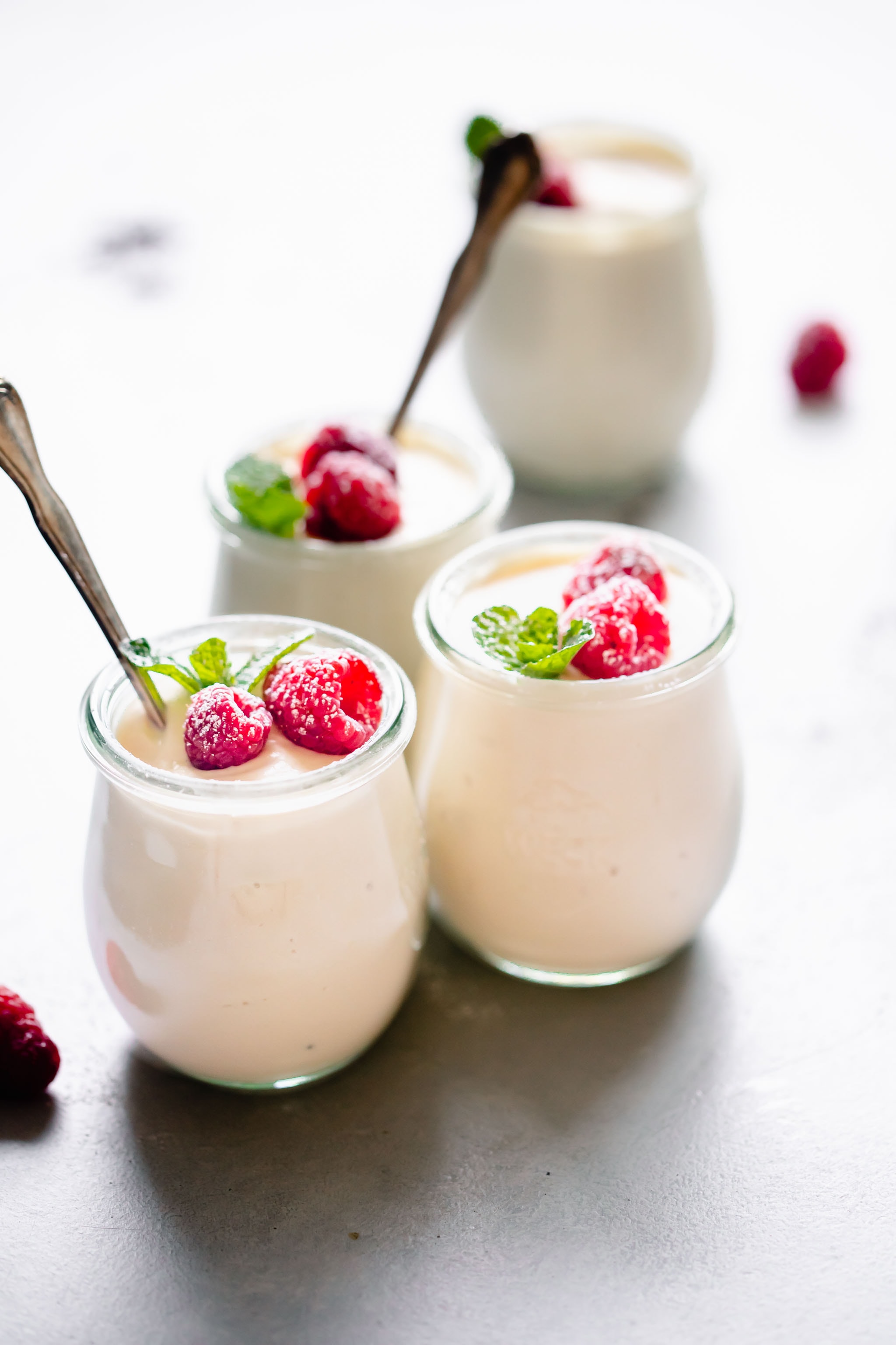 Four jars of ricotta mousse topped with raspberries.
