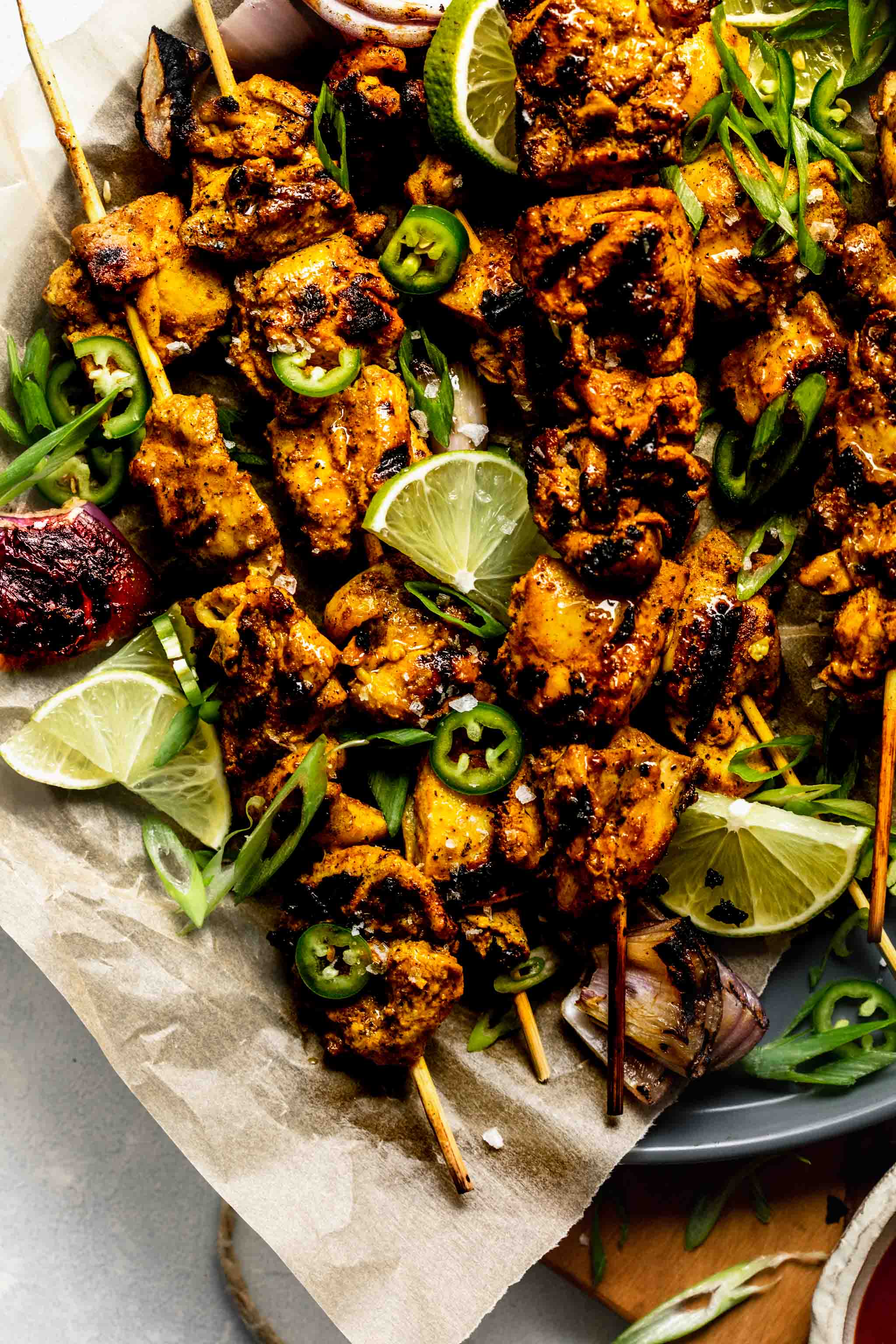 Close up of curry chicken skewers on grey plate with parchment paper.