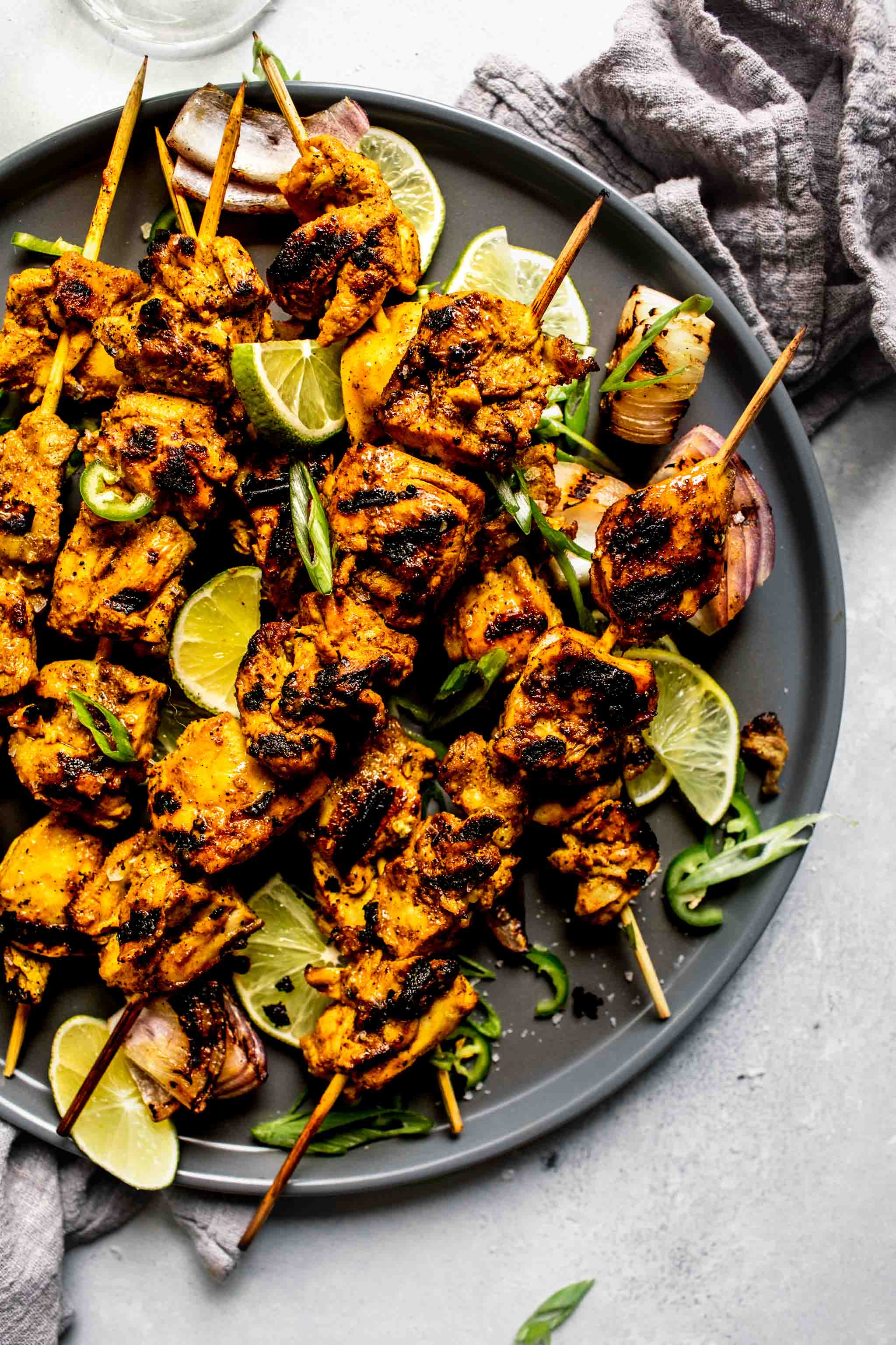 Close up of curry chicken skewers on grey plate.