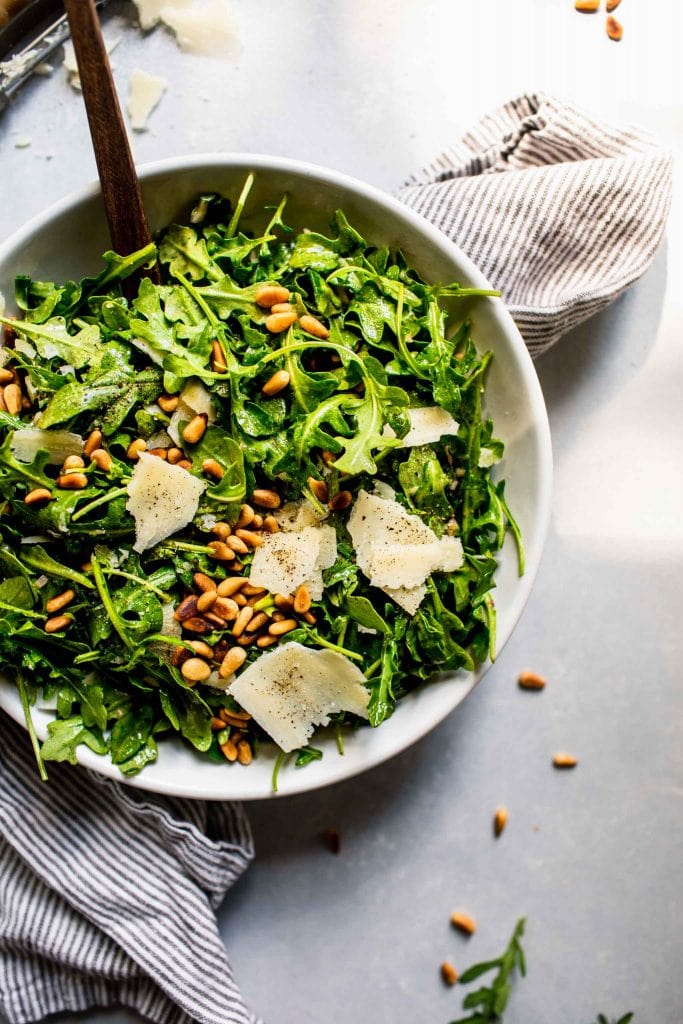 Overhead shot of arugula salad next to shaved parmesan.