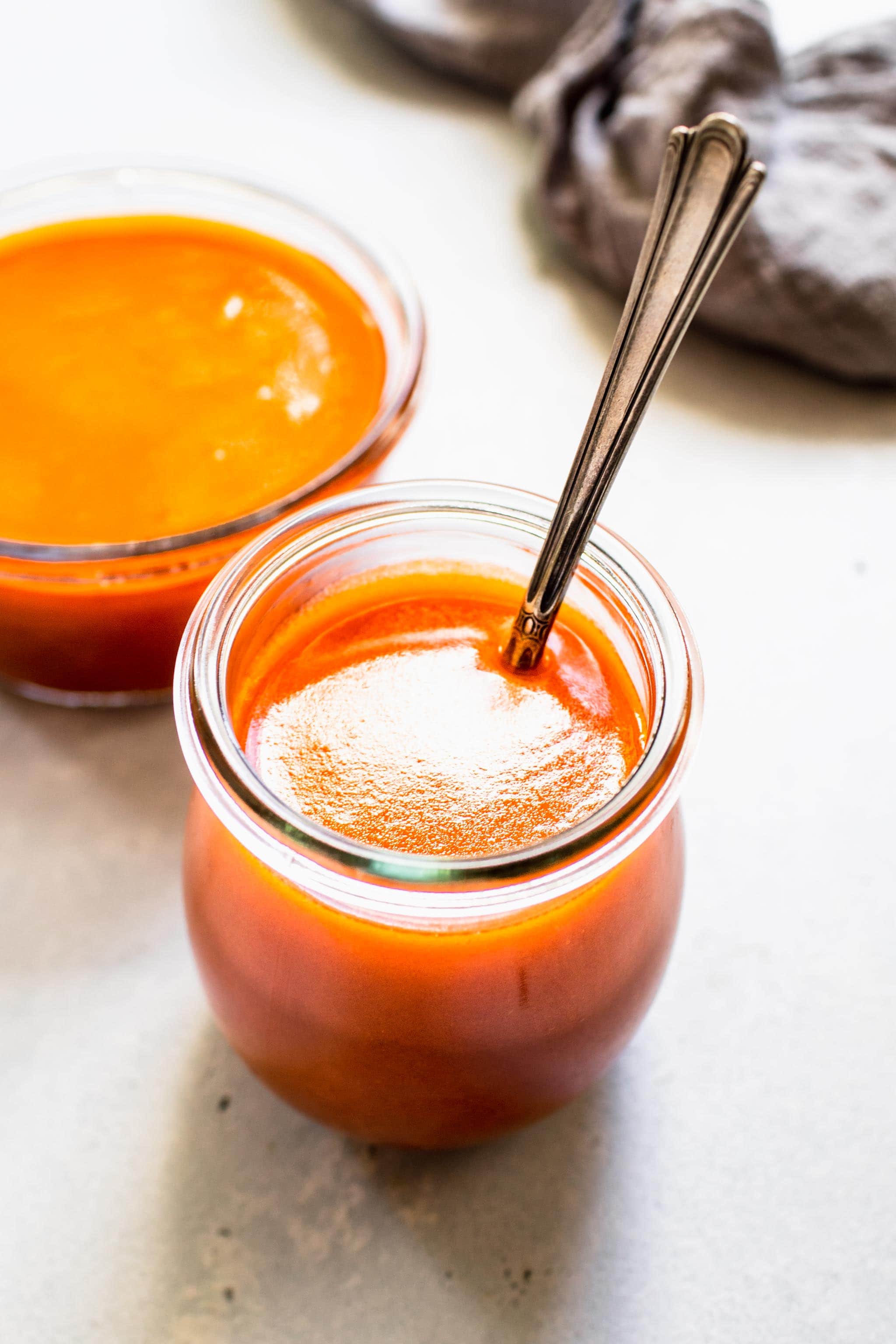 Spoon dipped into jar of homemade buffalo sauce.