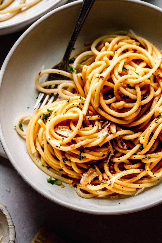 Overhead close up of swirls of spaghetti with fork in shallow bowl. 
