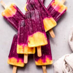 Cherry pineapple popsicles stacked on counter.