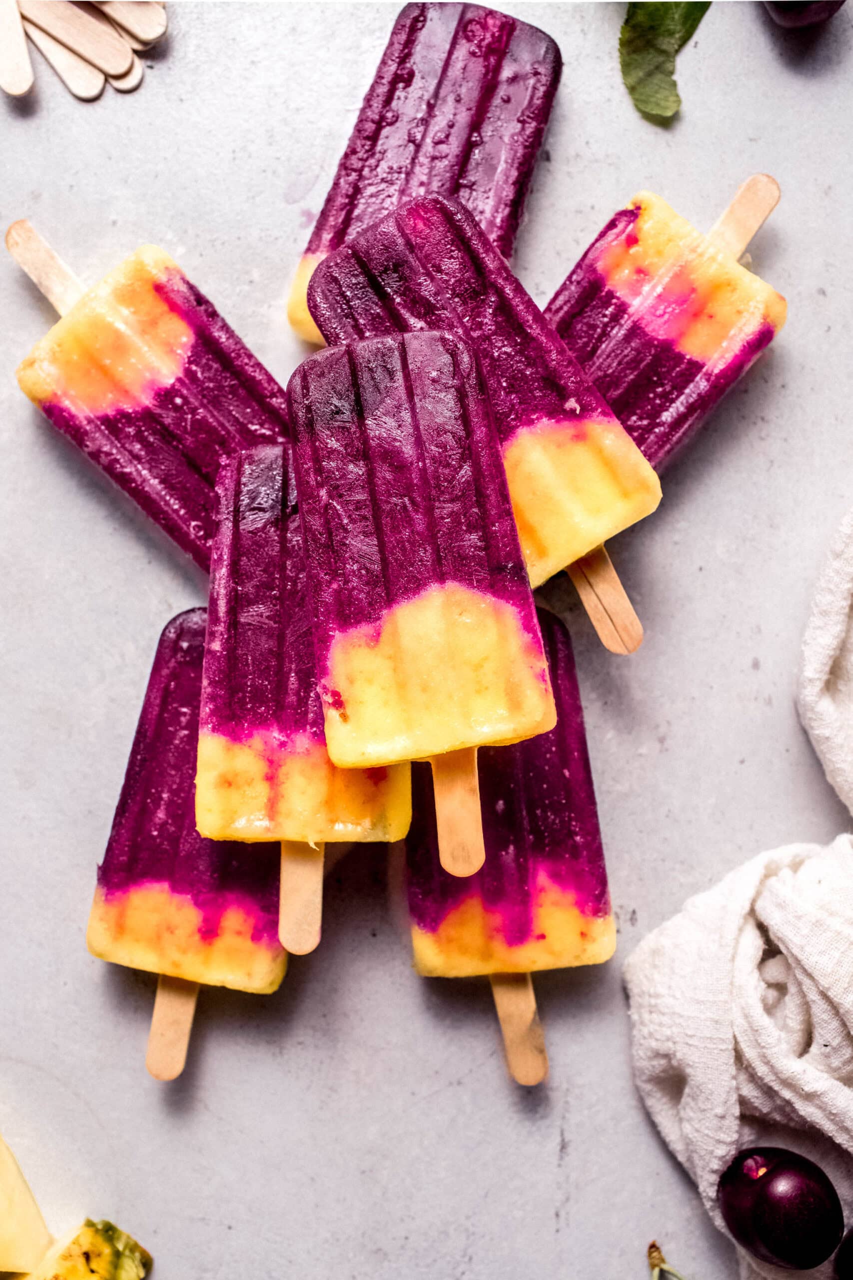 Cherry pineapple popsicles stacked on counter.