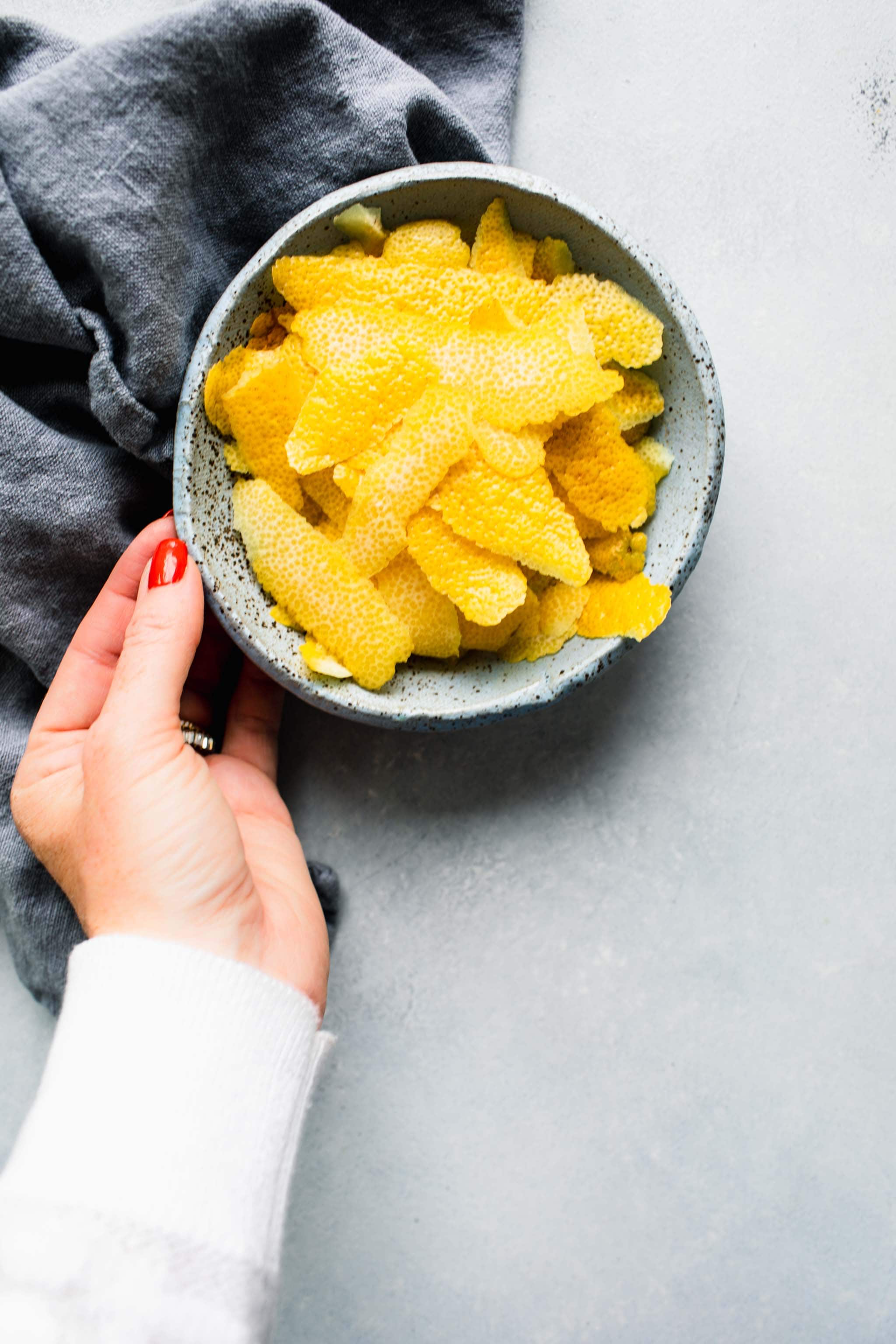 Hand holding bowl of lemon peels.