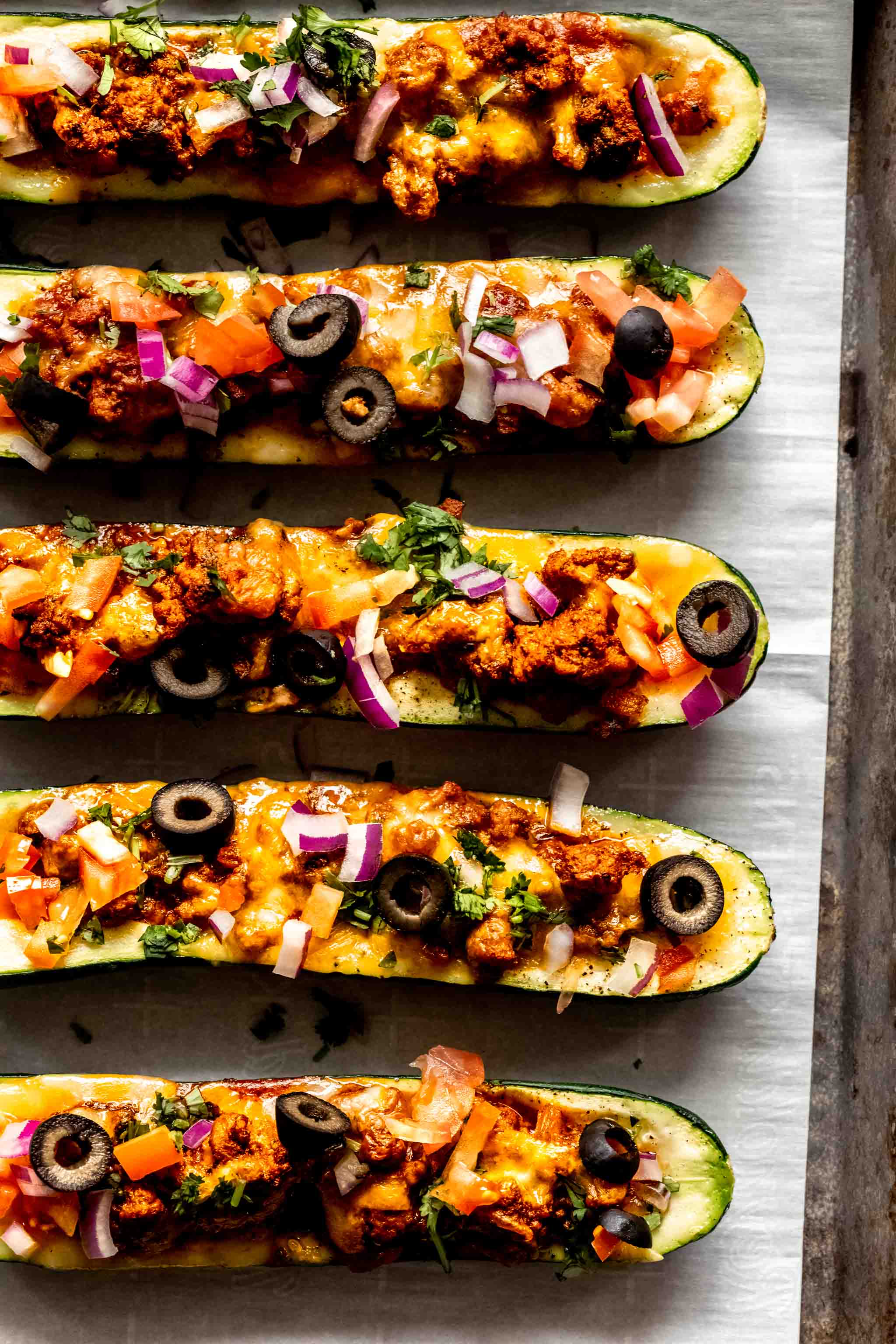 Cooked zucchini taco boats laid on baking sheet. 