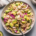 Overhead shot of avocado tuna salad in white bowl with serving spoon.
